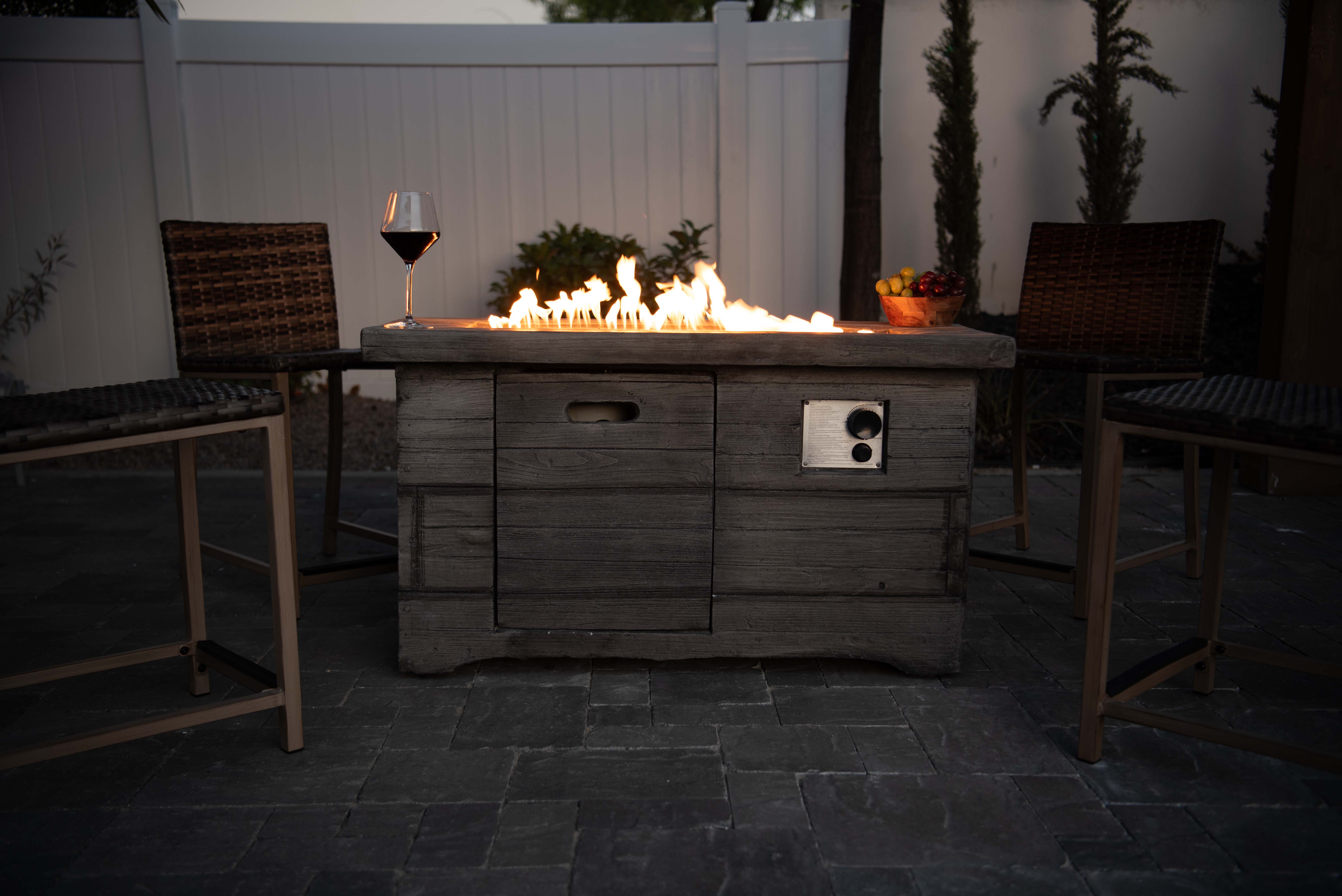 A cozy wood texture fire pit on a patio, surrounded by chairs and accompanied by a glass of wine in Temecula